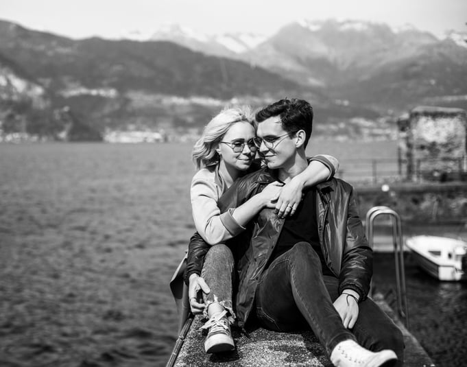 a couple sitting on a ledge overlooking the water