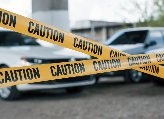 Police tape strung up across a crime scene in front of a parking lot