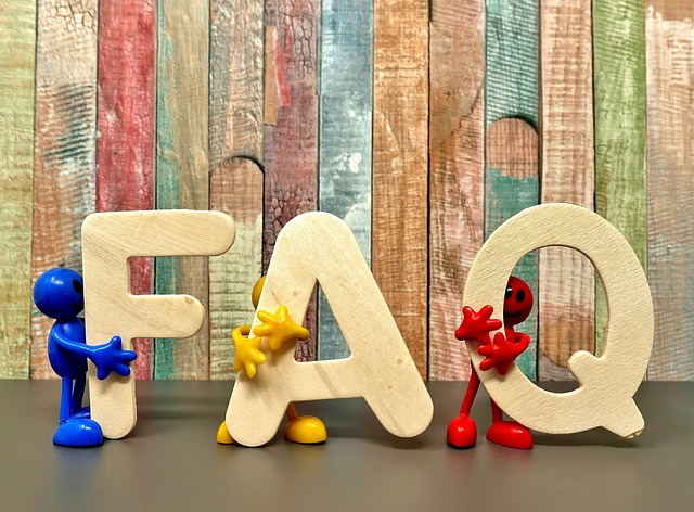 3 toy figures, each holding one letter of FAQ. Standing in front of painted wooden boards
