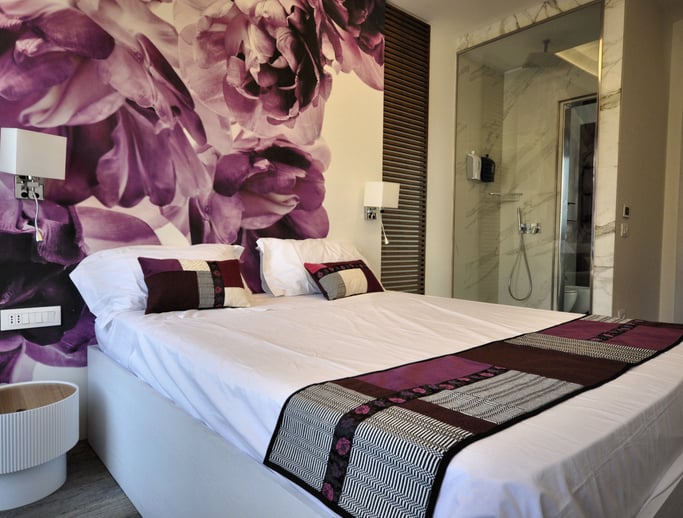 a bed with a large floral wallpapered wall