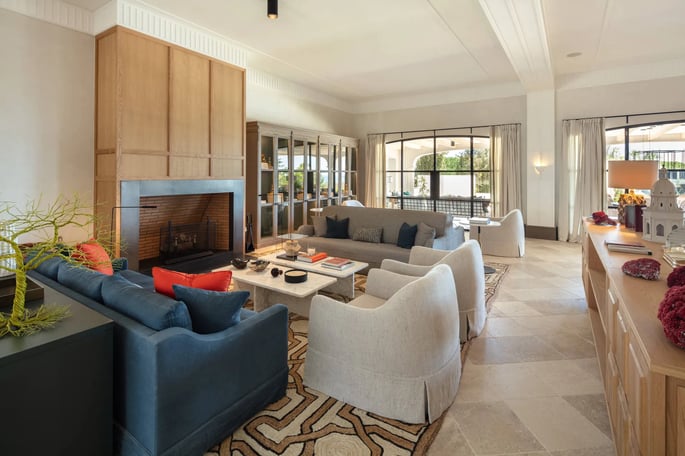 Seating area at Villa La Gratitud with designer sofas, fireplace, and garden views through windows.