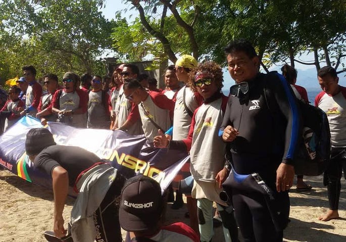 a group of people standing around a man in a wetsuit