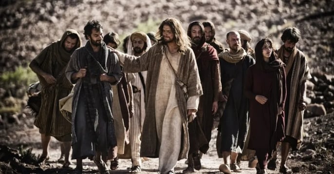 jesus walking down a dirt road with a group of people