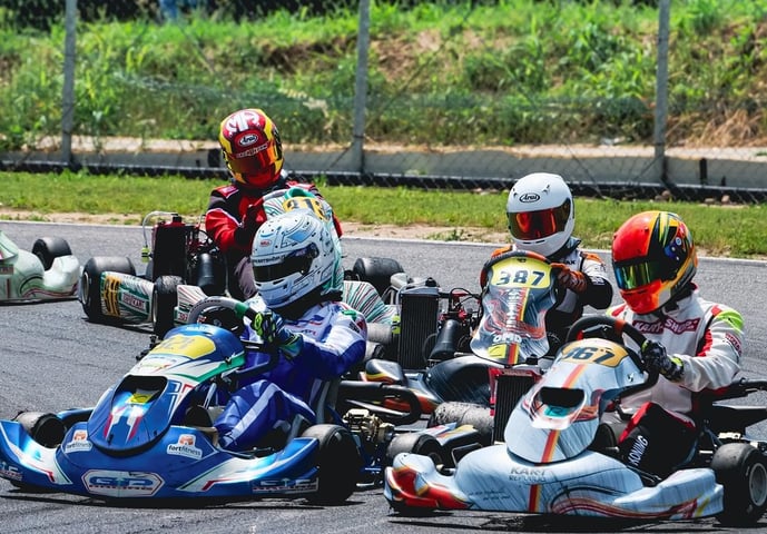 Quatre karts serrés sur une piste, pilotes en position compétitive lors d'une course.