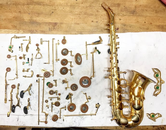 un saxophone soprano entièrement démonté avec ses clefs disposés à côté