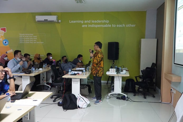 a man standing in front of a classroom with a speaker