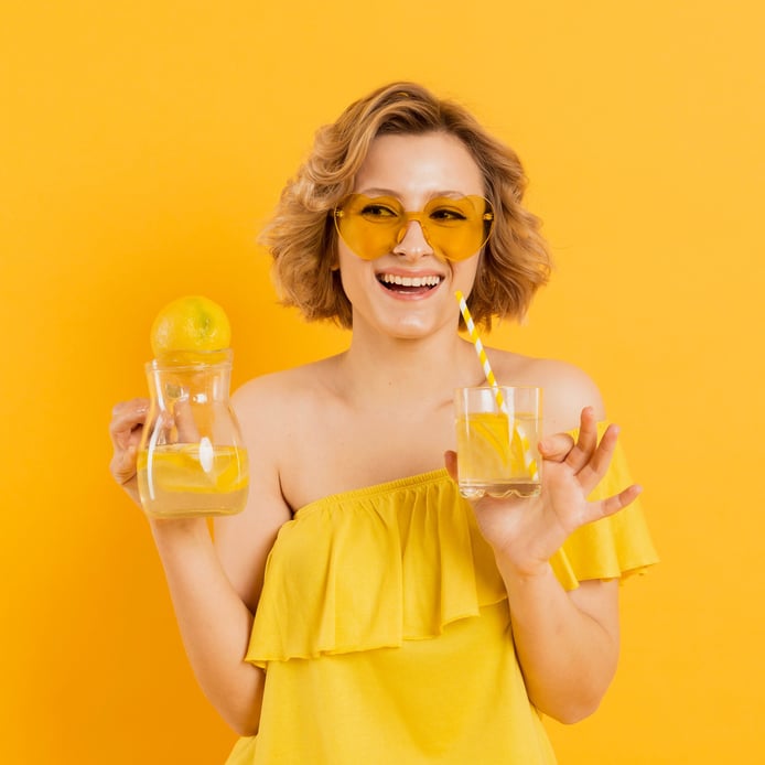 a woman in a yellow dress holding glasses of lemonade