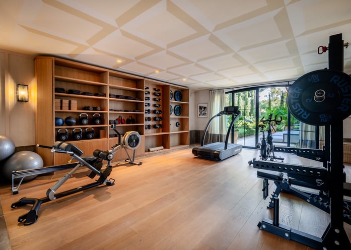 Villa La Gratitud’s gym with full range of fitness equipment, free weights, and garden views