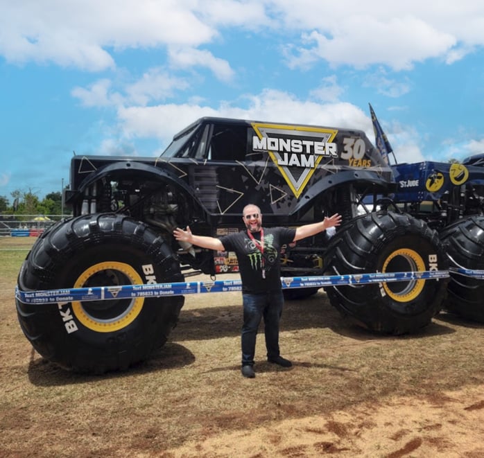 a man standing in front of a custom wrapped monster truck