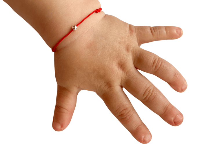 a child's hand holding a bracelet with a red string bracelet
