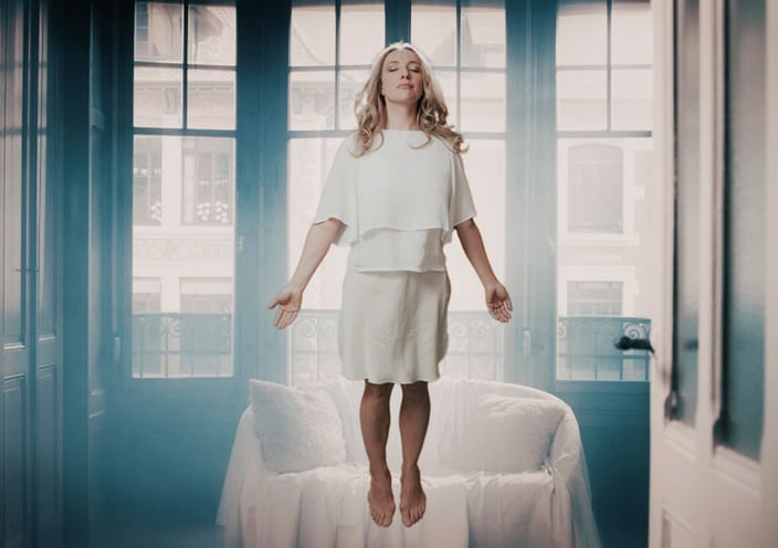 a woman in a white dress floating in front of a window