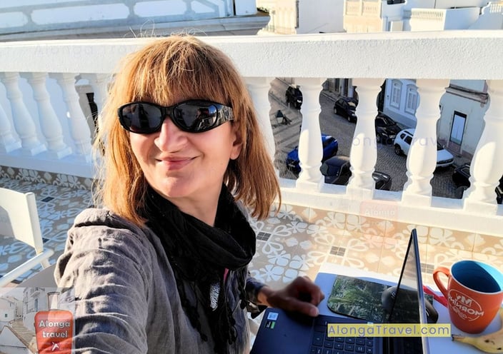 Alonga travel author working on a computer on a rooftop terrace in Portugal with a great view.  