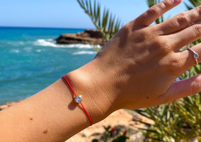 a woman's hand holding a bracelet with a red bracelet