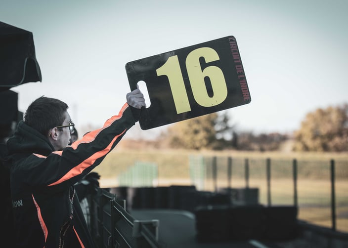 a man holding up a motorsport sign that says 16