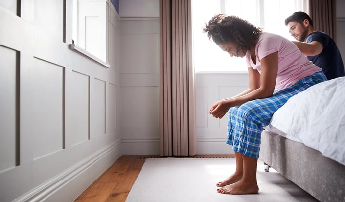 a man and woman sitting on a bed in health behaviour change