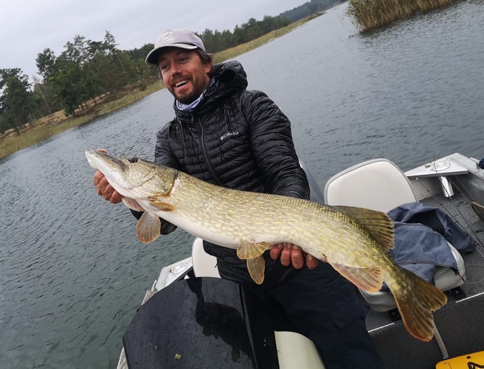 un homme est sur un bateau avec fishing escape sweden il à pêché un gros brochet en suède.