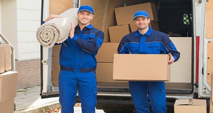 two men in blue uniforms carrying a large roll of paper towels