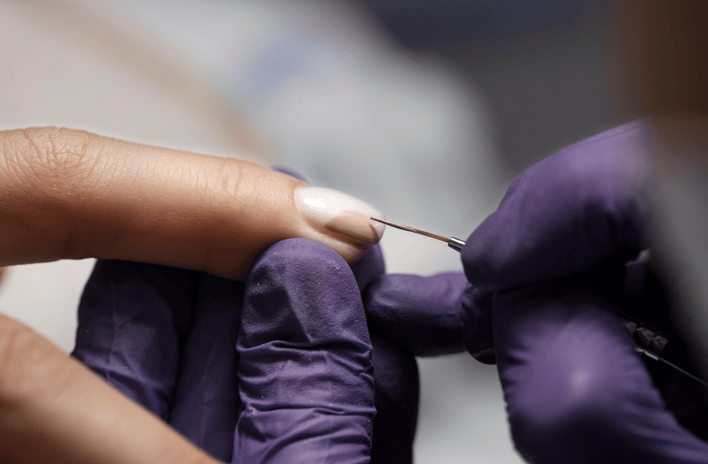 a person in purple glove holding finger doing nails