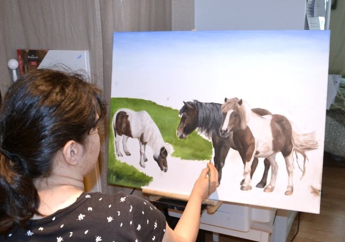 a woman is painting a picture of ponies