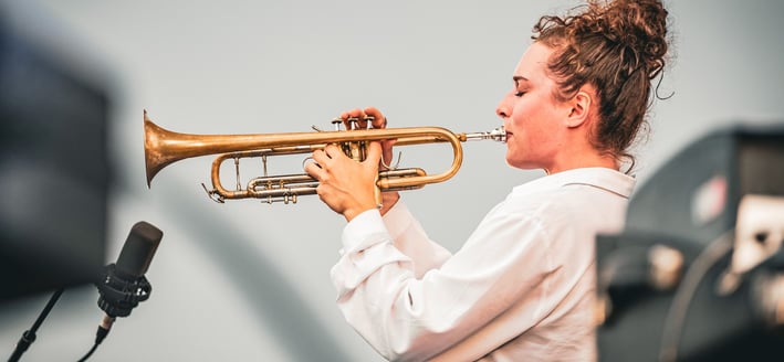 une femme en chemise blanche et trompette au Festival de Jazz de Saint-Omer