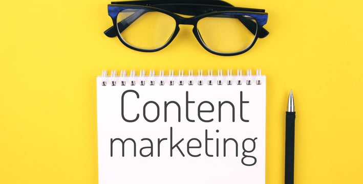 Notebook with the words Content marketing against a yellow background