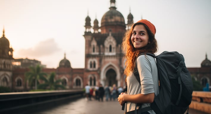 a woman with a backpacker on a bridge over looking at a building in Mumbai