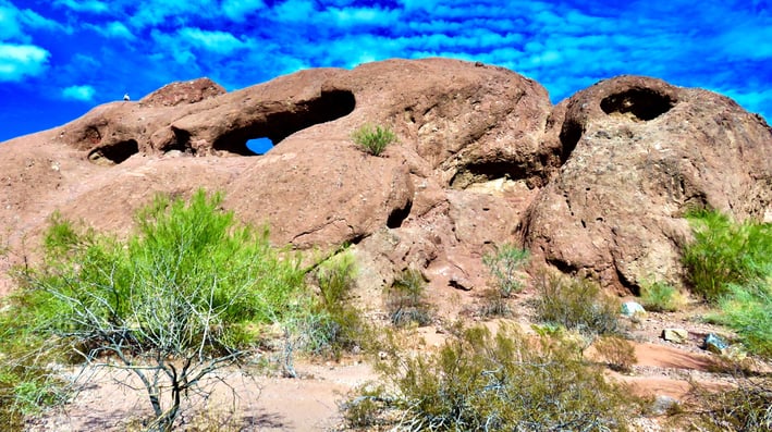 a rock formation in the desert with a blue sky and clouds