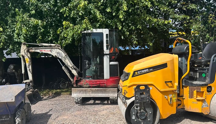 mini digger and roller in a commercial yard