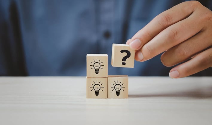 a person holding a wooden block with question mark