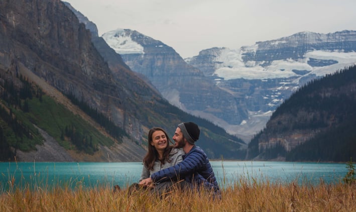 a man and woman sitting in a mountain field at Lake Louise