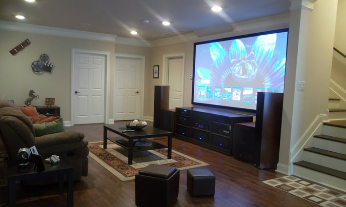 Large fixed frame projector screen mounted on a wall in a living room - home cinema room