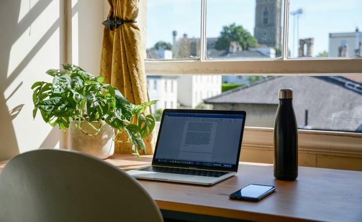 a laptop computer sitting on a desk with a phone and a bottle of water