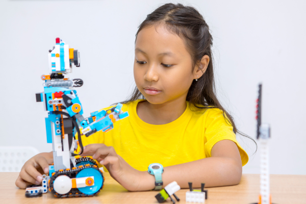 A young girl builds a robot with a STEM toy, inspiring creativity and problem-solving skills.