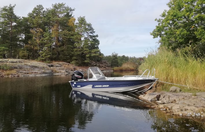 fishing escape sweden a un bateau "linder arkip" sur un lac en suède. il y a des pins, des rochers.