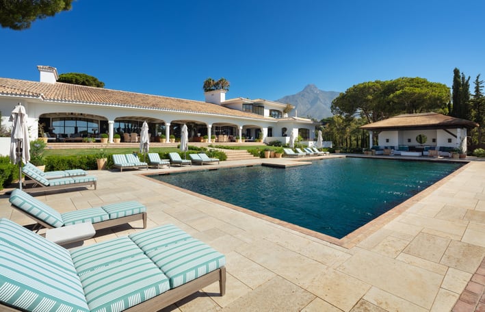 Expansive pool terrace at Villa La Gratitud, with sun loungers, covered porches, and mountain views.