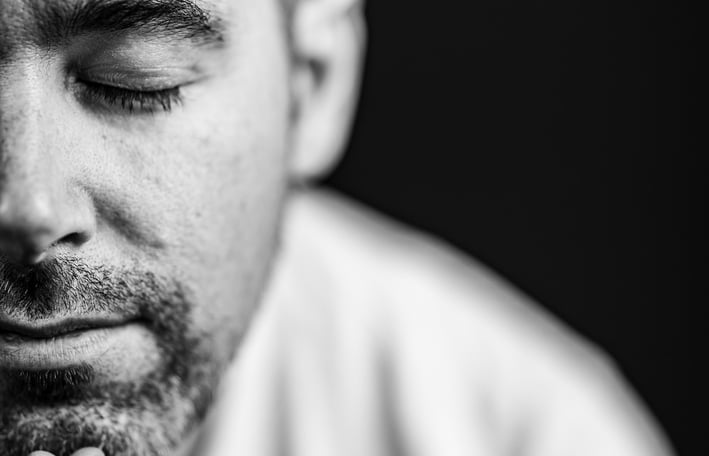 un homme avec une barbe fermant les yeux pendant une séance photo