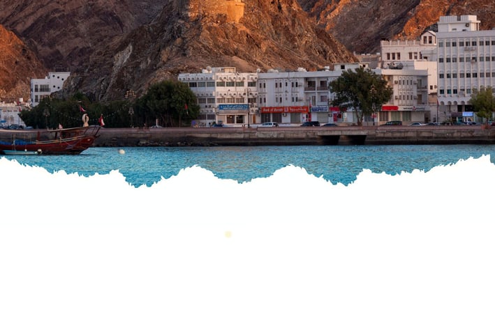 Passeio de barco em Muscat com vista para o Corniche, revelando a orla elegante.