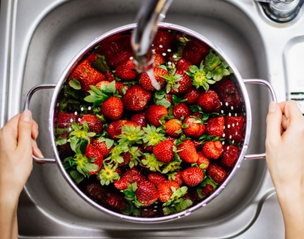 Someone washing strawberries in the sink