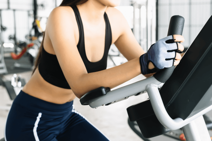 a woman in a sports bra top and gloves on a stationary bike