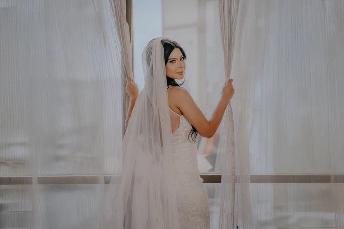 Novia con vestido blanco de espaldas abriendo cortina - Mejor fotógrafo de bodas en Guadalajara, Mx