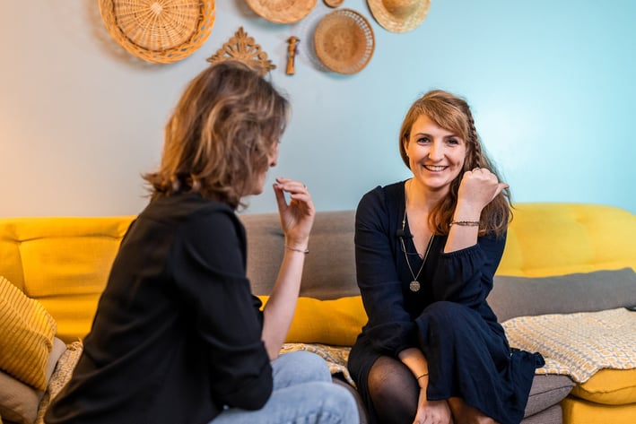 une femme assise sur un canapé parlant à une autre femme