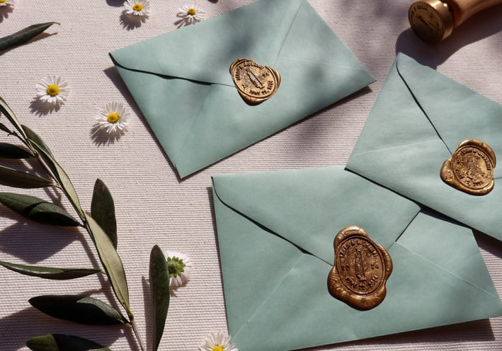 sage green envelopes with custom wax seal flowers and olive branches