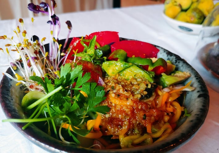 a bowl of food with a salad on a table