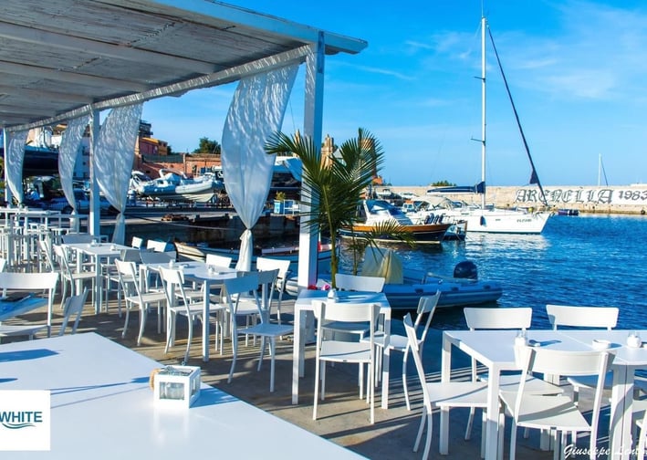 a restaurant with tables and chairs and a boat in the water