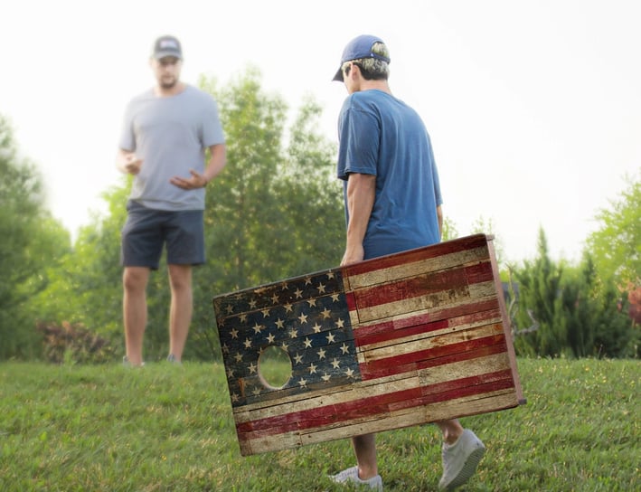 a man holding a corn hole board that is a flag