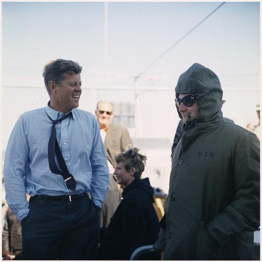 two men in suits and ties standing in front of a crowd