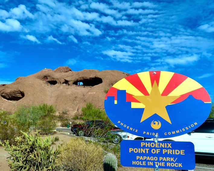 a sign that says phoenix point of pride Papago park/ hole in the rock in front brown rocks