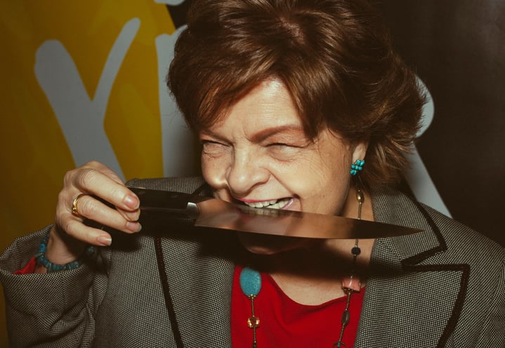 Mujer mayor divertida mordiendo un cuchillo y riendo para la marca de cuchillos Zwilling