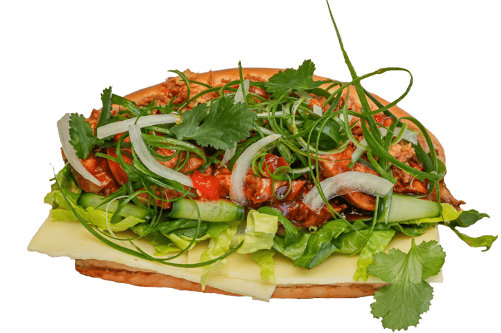 a chicken sandwich with korean bbq sauce, cheese, lettuce, spring onions and herbs