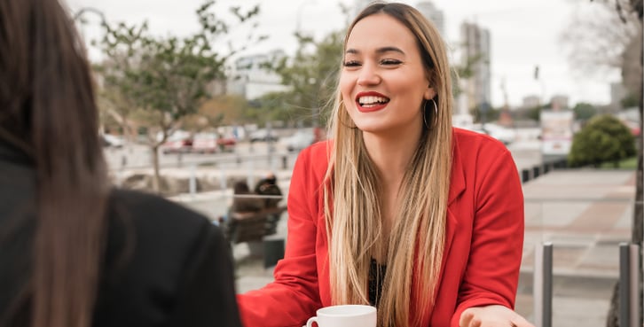 a woman sitting at a table with a cup of coffee
